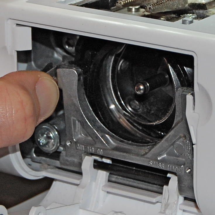 Press the lever on the top left of your bobbin area to release the metal/black plastic housing